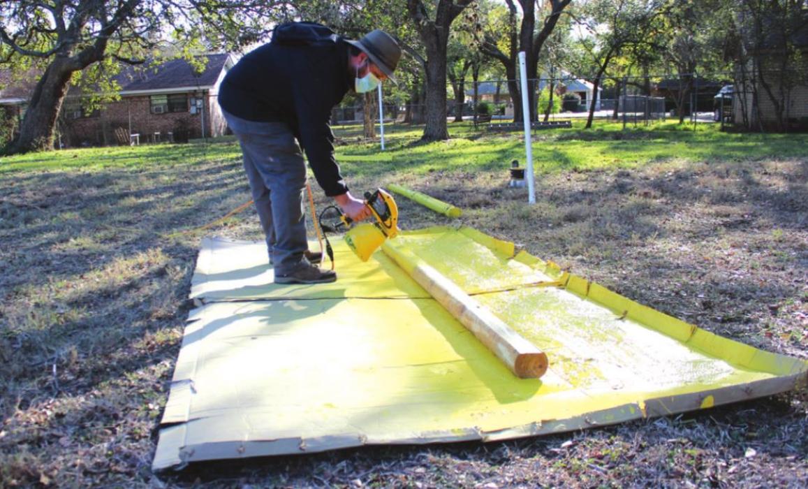 Allen Cooper is shown here Tuesday painting timbers to aid in the new parking set-up for the Trail of Lights.