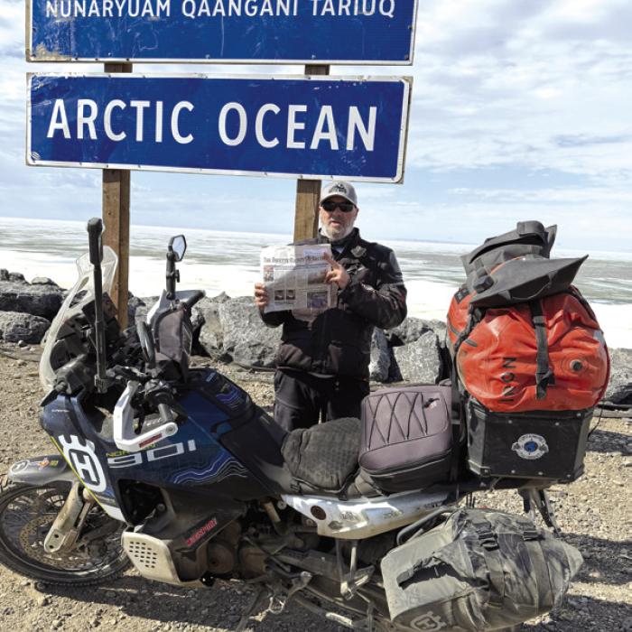 Chris Westfall stands at the sign marking Tuktoyaktuk, Northwest Territories, the northernmost community in Canada accessible by road, after completing an 11,724-mile motorcycle journey. Westfall timed his arrival for the June 21 summer solstice to experience the Arctic’s famous “midnight sun.”