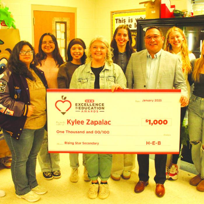La Grange High School teacher Kylee Zapalac, pictured above right behind her name on the check, poses with her students, and La Grange Principal John Pineda, after being surprised in her classroom Thursday with the news that she has been named a finalist, and $1,000-winner, in HEB’s Excellence in Education Awards.