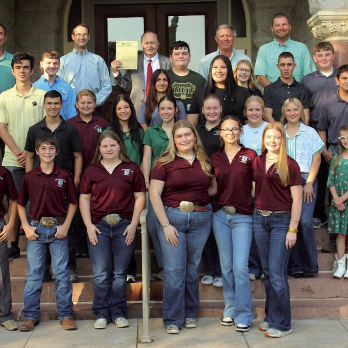 Fayette County 4-H students (with the county Leadership Council members in front) stand outside the courthouse Wednesday morning after they gave a report on their activities to the Commissioners Court and County Judge Dan Mueller (who is holding a proclamation he signed designating Oct. 4-10 as National 4-H Week in Fayette County.) Photo by Jeff Wick