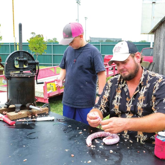 Greg Kubenka and his son Keeston demonstrate sausage making. Kubenka said the recipe included mostly pork with a little axis deer. They smoked it on site and gave away samples that afternoon.
