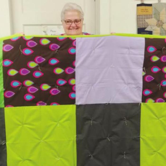 Annie Mae Kappler, Nancy Pietsch and Cindy Heselmeyer display one of the quilts that were made for Lutheran World Relief.