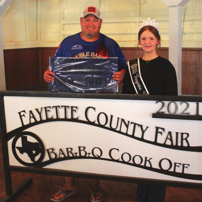 The Champion Pork Butt at this year’s Fayette County Fair was made by the Double Barrel Cookers of Cat Springs, head cook Todd Nelson. Also shown is Fayette County Fair Queen Charlee Wessels.