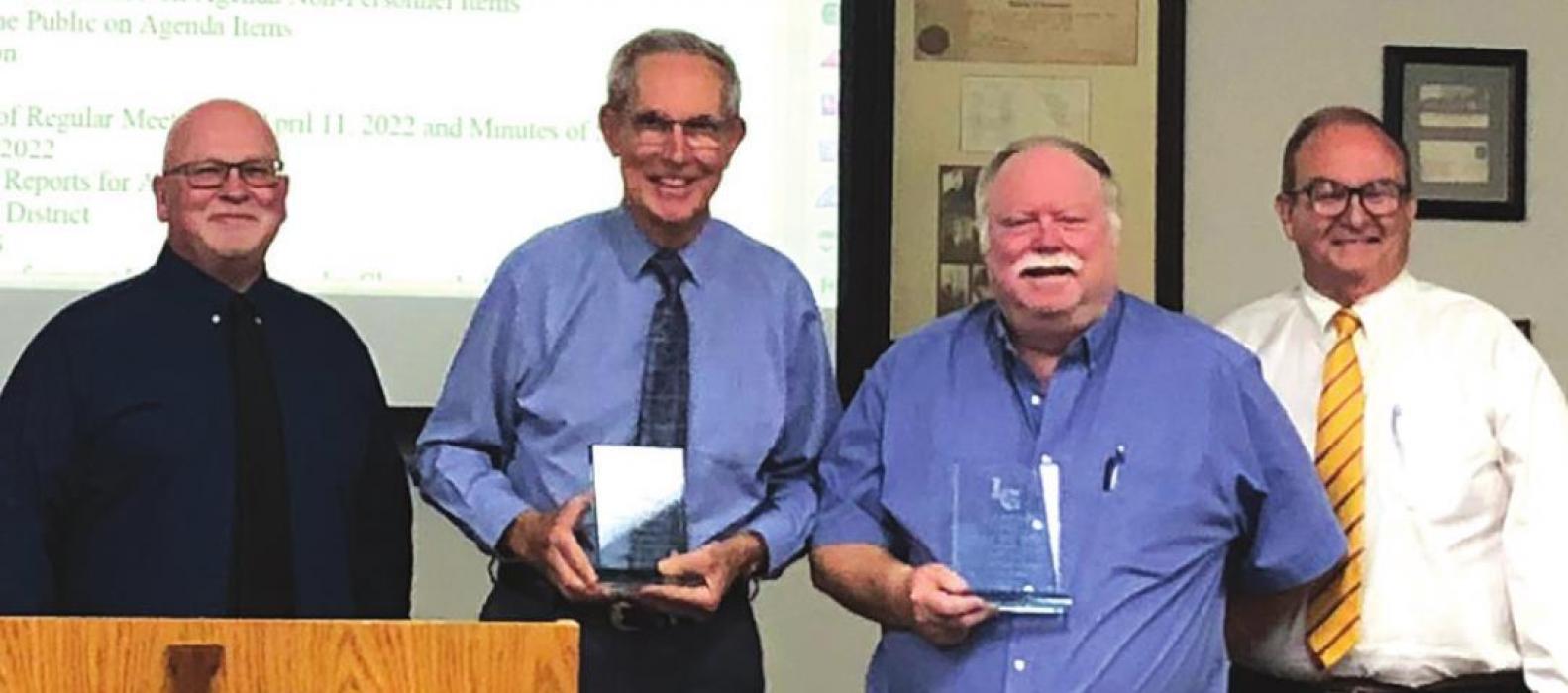 LGISD School Board president Gary Drab, left, and superintendent William Wager, right, present outgoing board members Dr. L. Donald Mayer and Greg Trlicek with awards of appreciation for their combined 48 years of service to the district.