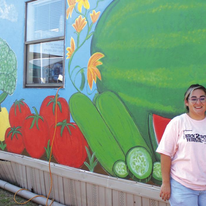 Juanita Navarro stands next to the mural she painted in the Tejas Clinic community garden, site of Saturday’s festival. Photos by Jeff Wick