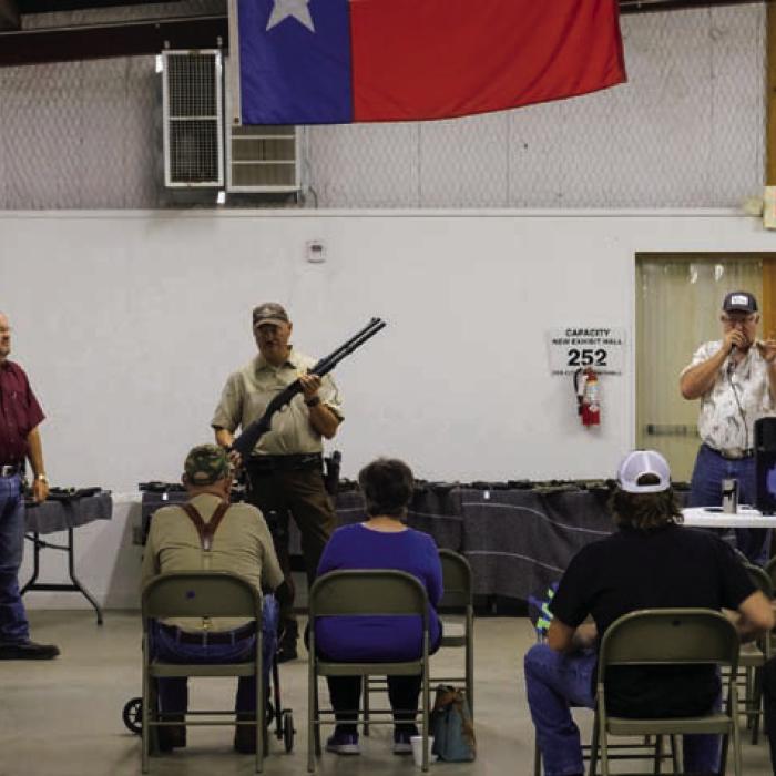 Sgt. Ron Naumann holds a 12 gauge Remington 870 shotgun as auctioneer Lee Fritsch (right) calls out the bids at a gun auction hosted by The Fayette County Sheriff’s Office on Thursday, Sept. 28. The Sheriff’s auction included more than 100 firearms that have been seized and forfeited in criminal cases. The auction raised about $32,000 that will be used to supplement the Sheriff’s Office budget. Photo by Andy Behlen