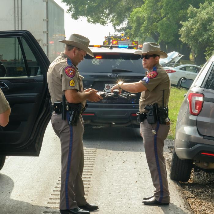 Crash investigators with the Texas Department of Public Safety prepare to launch a drone to capture overhead images of the crash scene. The driver of the white Hyundai car in the background died in the crash