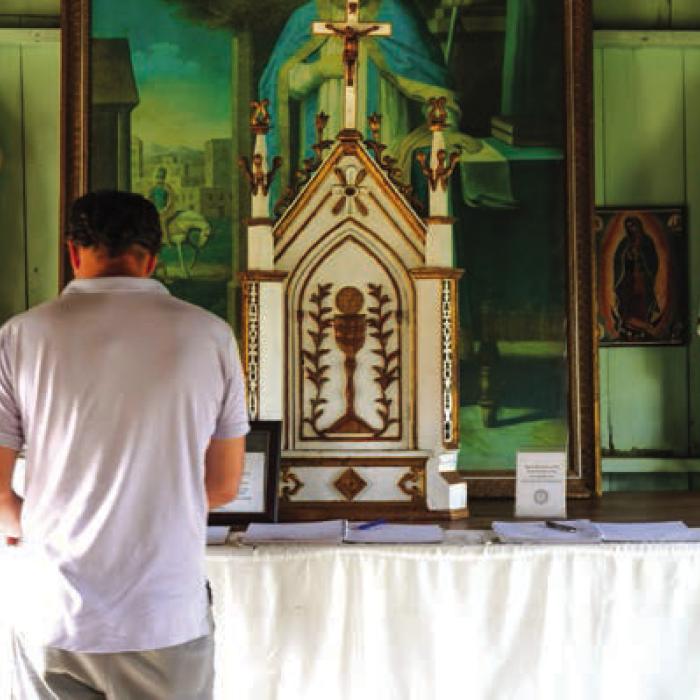 Inside St. Martin’s in Warrenton, the world’s smallest active Catholic Church. There are notebooks on the altar, in which people can write prayer intentions. Photo by Andy Behlen
