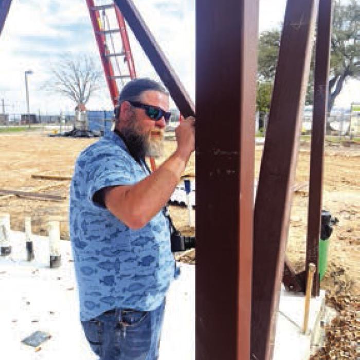 Andy Behlen signs a beam at the construction site of the new Hostyn church. Photo by Jeff Wick