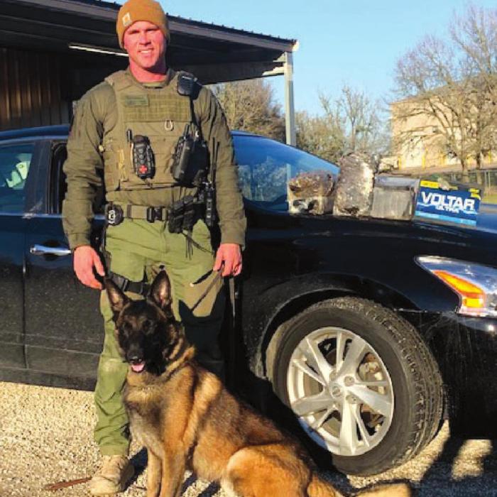 Sgt. Randy Thumann and K-9 partner Kolt with the 15 lbs. of heroin in a car battery found inside the car.