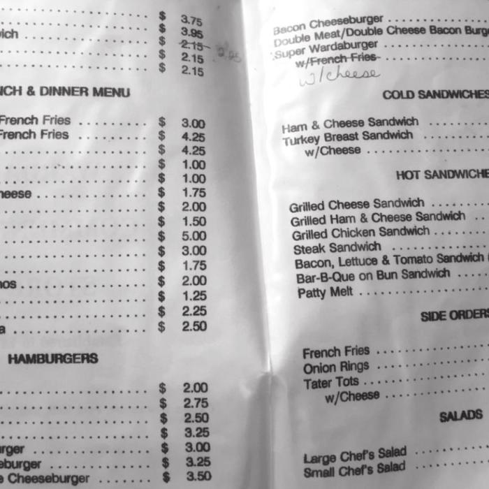Clockwise from top, left: Domino playing at the Warda Store, an old newspaper ad showcasing some real consistency in pricing, and a copy of an old menu with the “Warda Burger” costing only $2 and the “Trucker’s Breakfast” only $3.75.