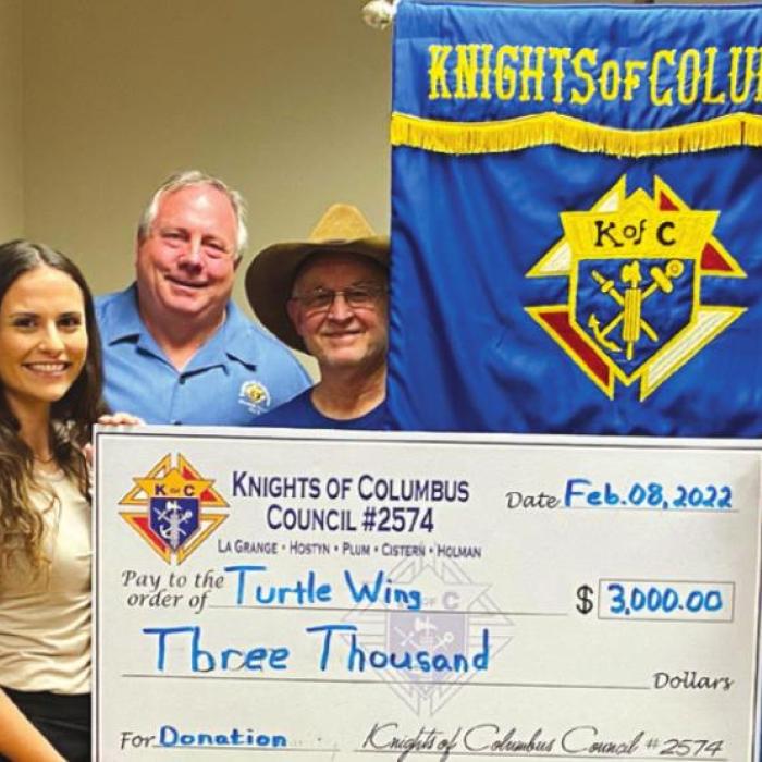 Pictured from left are David Shimek, Hector Cervantes, Garry Schellberg, Destiny Psencik (Turtle Wing Foundation Executive Director), Charles Youngblood, Jim Kothmann; other side of the flag (right side), front row: Philip Rocha, Ralph Dunk, Marcus Recek and Pat Lyons.