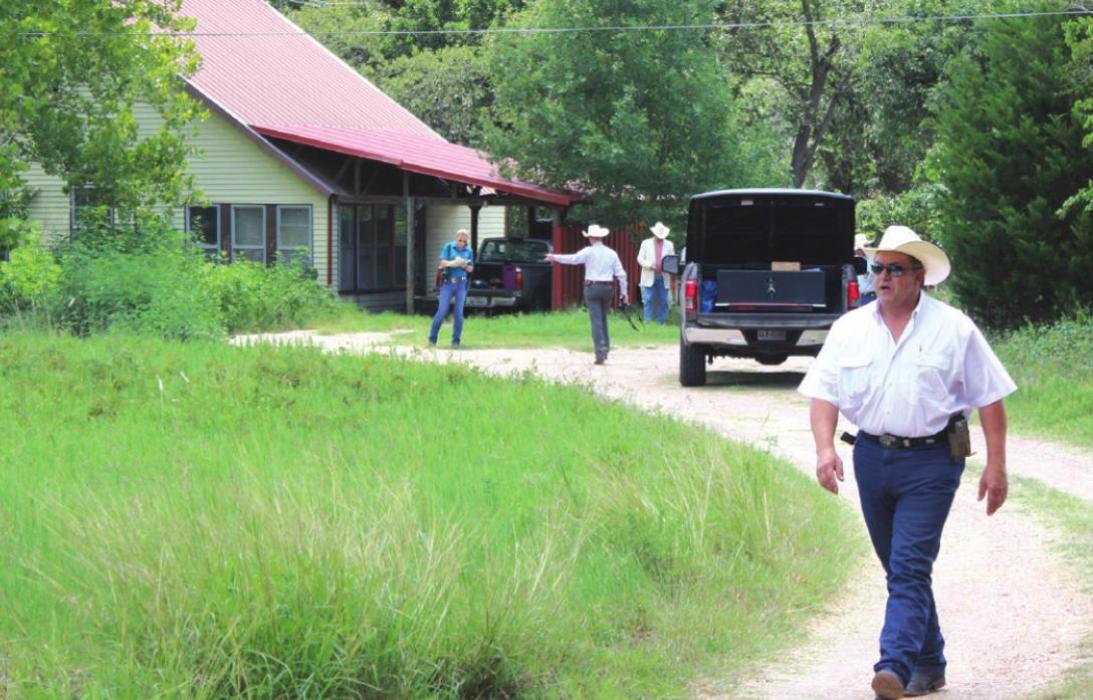 As Texas Rangers and county officers continue their investigation in the background, Fayette County Sheriff Keith Korenek walks up the driveway of the home on Creamer Creek Road outside La Grange where Jeremy Cornwell was shot and killed in 2017. Record File Photo by Jeff Wick