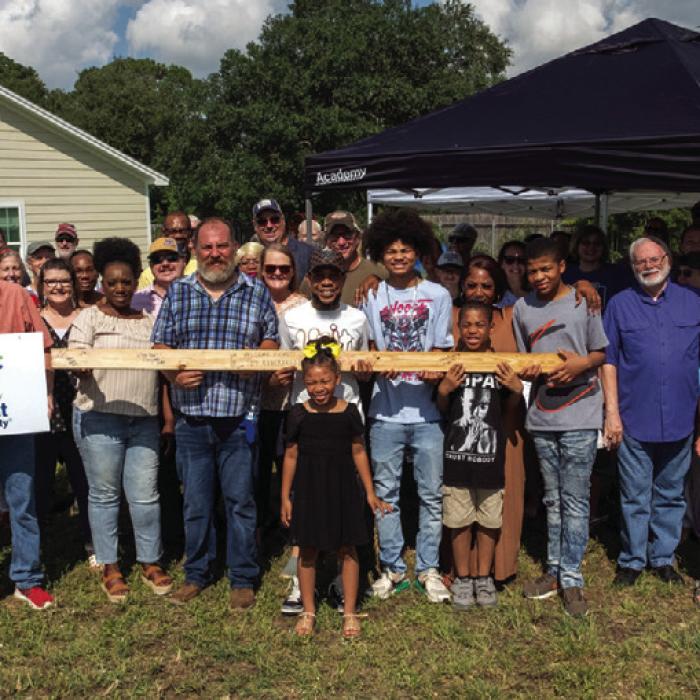 Johnny Wright (center), surrounded by family, friends, Habitat for Humanity volunteers and local supporters, stands on his future homesite in the Hope Hill neighborhood of La Grange. They’re holding a signed 2x4 with words of support that will be used in the construction of his future home. Photos by Andy Behlen