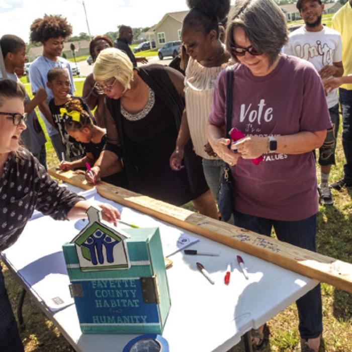 Supporters gather to write words of encouragement on a 2x4 that will be used in the construction of Wright’s home.