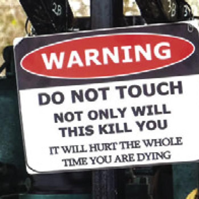 A rather descriptive signs warns folks not to touch this antique engine demonstration.