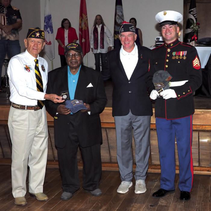The oldest and youngest veterans in attendance were recognized. Pictured (from left) are Danny Vyvjala (Commander of Post 94 in Flatonia) presenting a hat and coin to the oldest veteran, Mr. BJ Anderson, and Stephen Barthelme (Commander of Smithville VFW Post 1309) presenting a hat and coin to the youngest veteran, Montana Olle.