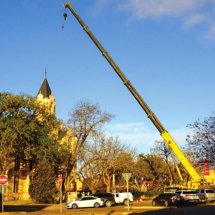 Above, a scene from early Monday morning as Ray’s Crane Service set up a crane on the east side of the courthouse. Upper photo, two clocksmiths from Verdin Clock Company of Ohio work on the mechanism inside the clock tower. Photos by Andy Behlen