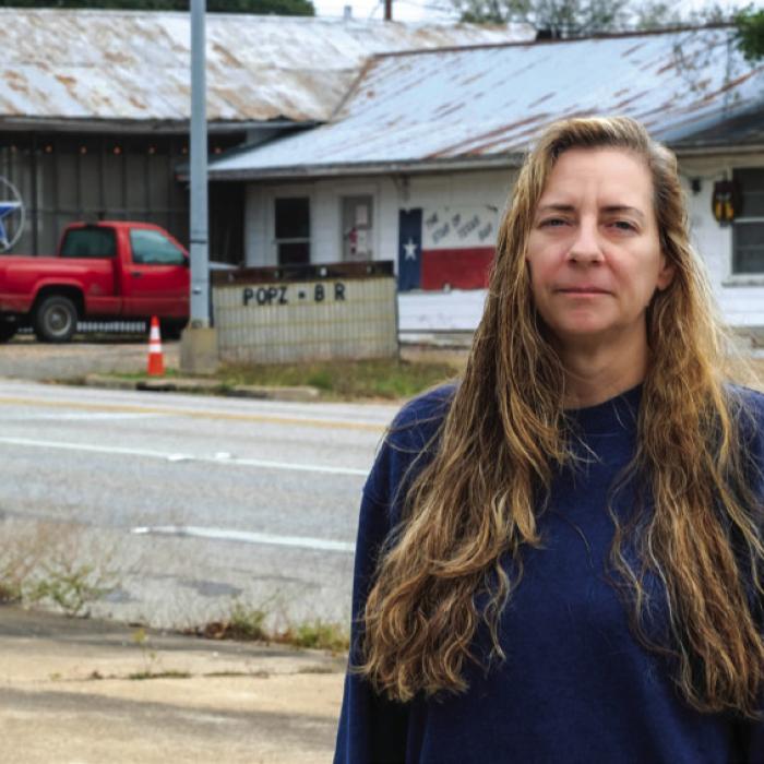 Susan Williams stands on the curb across Travis St. from Pops Star Bar on Sunday, Dec. 21. Photo by Andy Behlen