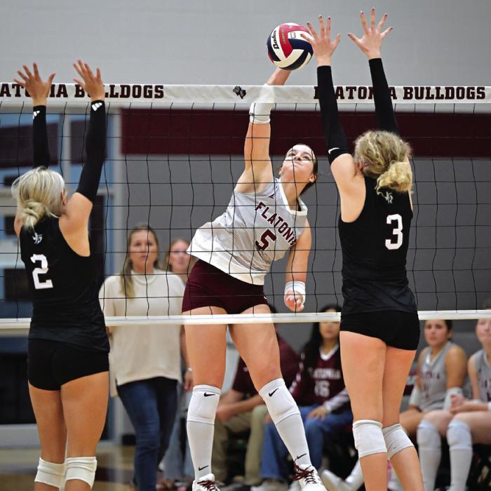 Flatonia’s Abbie Uzzell spikes a ball between Fayetteville players Aubree Graeter, left, and Scotti Beseda, right. Photo by Stephanie Steinhauser