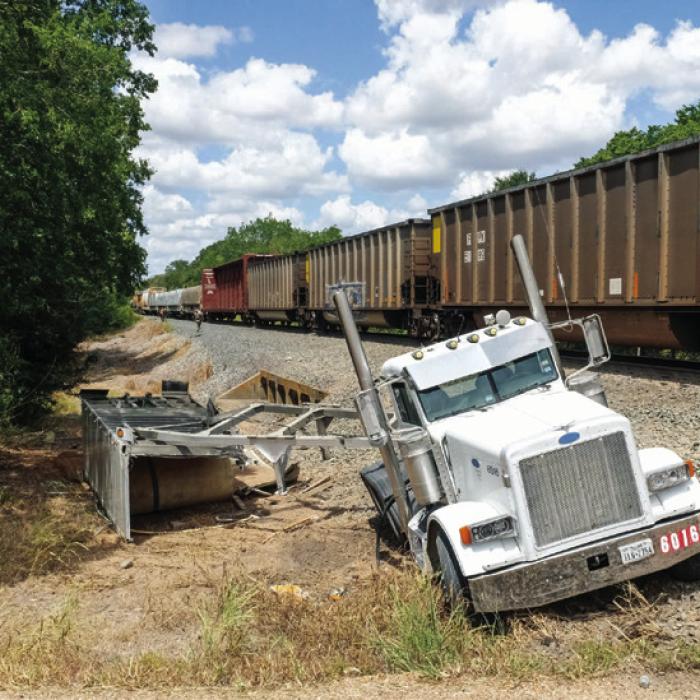 A Union Pacific train smashed through an 18-wheeler trailer hauling a load of gravel on Huelsebusch Rd. Tuesday around noon. The truck-tractor and part of the trailer ended up on the south side of the tracks (pictured left) while the back half of the trailer came to rest on the north side of the tracks (right). Photos by Andy Behlen