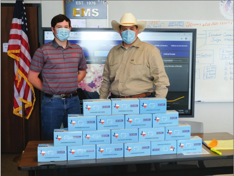 Fayette County Emergency Management Chief Craig Moreau (right) and intern Brendan Gilbreath (left) pose with some of the thousands of face masks that Schulenburg native Carman Kobza provided to the County’s emergency management department. Photo by Andy Behlen