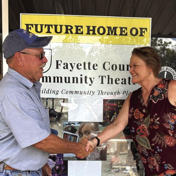 Allan Minarcik of Minarcik Construction Company shakes hands with Heather Barthelme, Fayette County Community Theatre Executive Director after signing the contract to begin work on the downtown LG theatre in the old Prause Building.