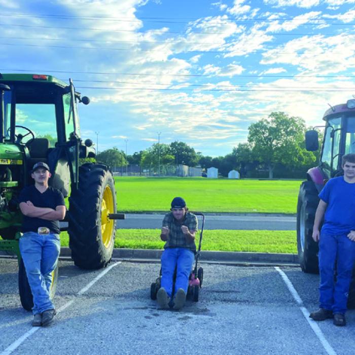 From left to right, La Grange High School students Luke Chovanec, Alan Hepner and Mason Oppermann with the machines they drove to school Friday. Chovanec and Oppermann drove their tractors, and yes, that is Hepner sitting atop a push lawn mower. Photo by Deacon Wick