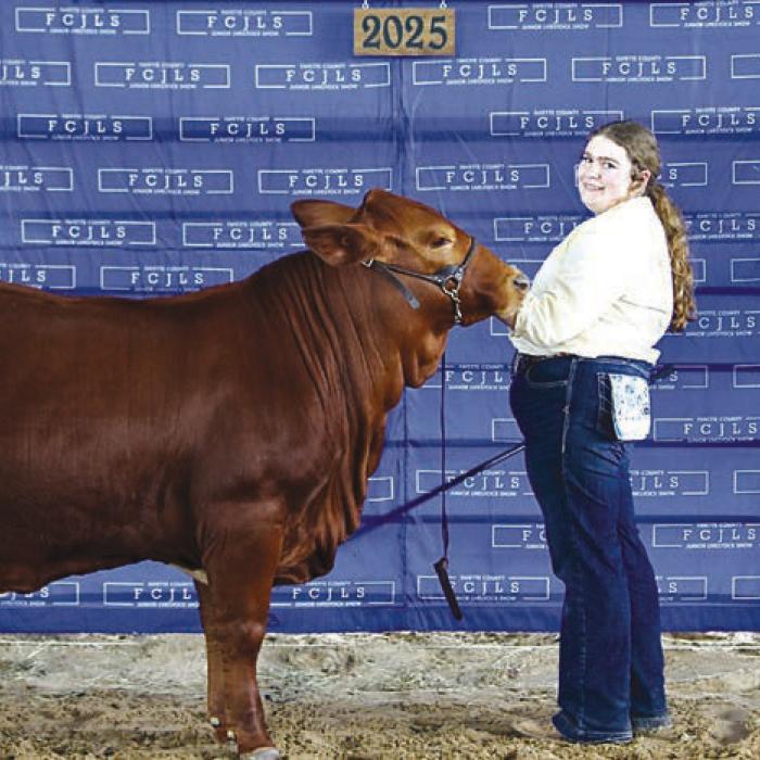 Grand Champion American Heifer - Rheagan Karisch, Pure Country 4-H; Caleb Boardman - Heifer Judge and Rilan Karisch - Holding Bag.