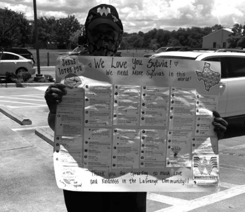 Sylvia at Whataburger holding up a poster Holly Rangel created with kind comments posted on Facebook about Sylvia’s interactions with people at the restaurant.