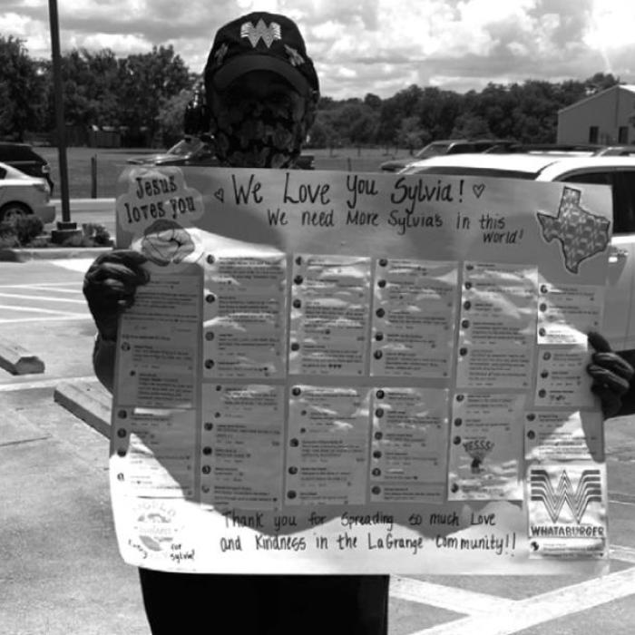Sylvia at Whataburger holding up a poster Holly Rangel created with kind comments posted on Facebook about Sylvia’s interactions with people at the restaurant.