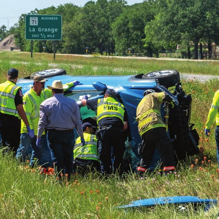 La Grange firefighters and Fayette County EMS personnel work to get inside a car that crashed on SH 71 Monday. The driver died at the scene. Photo by Andy Behlen
