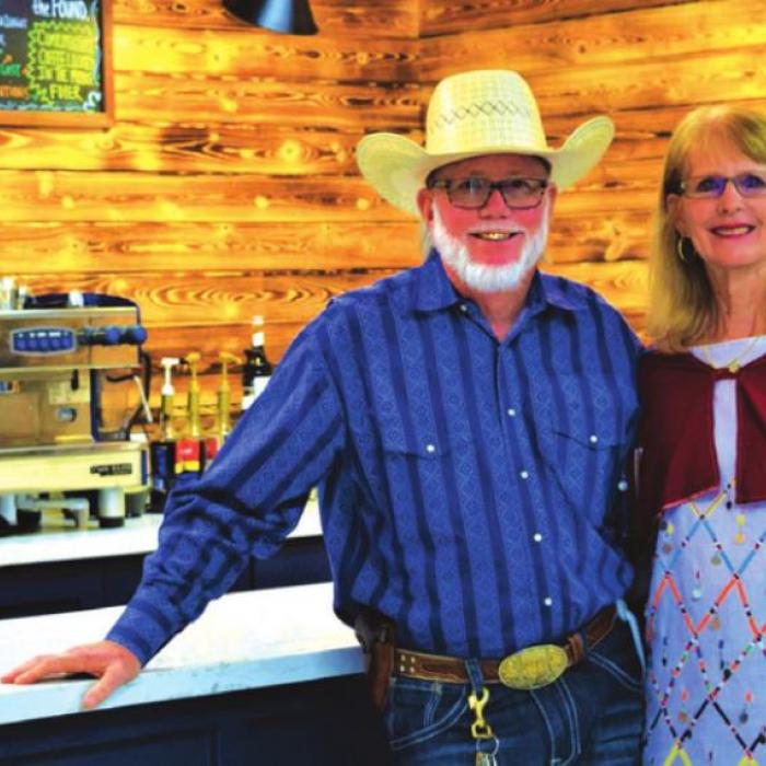 Dennis and Jan Hill in front of the coffee bar at church. Jan is wearing authentic Maasai clothing from one of their mission trips to Kenya.