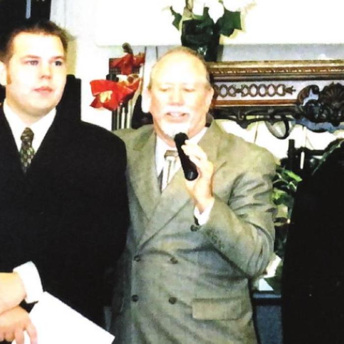 Kolbe Hill, left, at his ordination 16 years ago, as his father-in-law Dennis Hill speaks on the microphone.