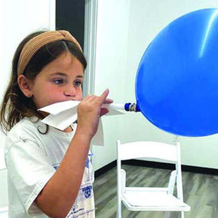 Students participate in a balloon rocket balloon experiment (above), and a flight simulation game (below).