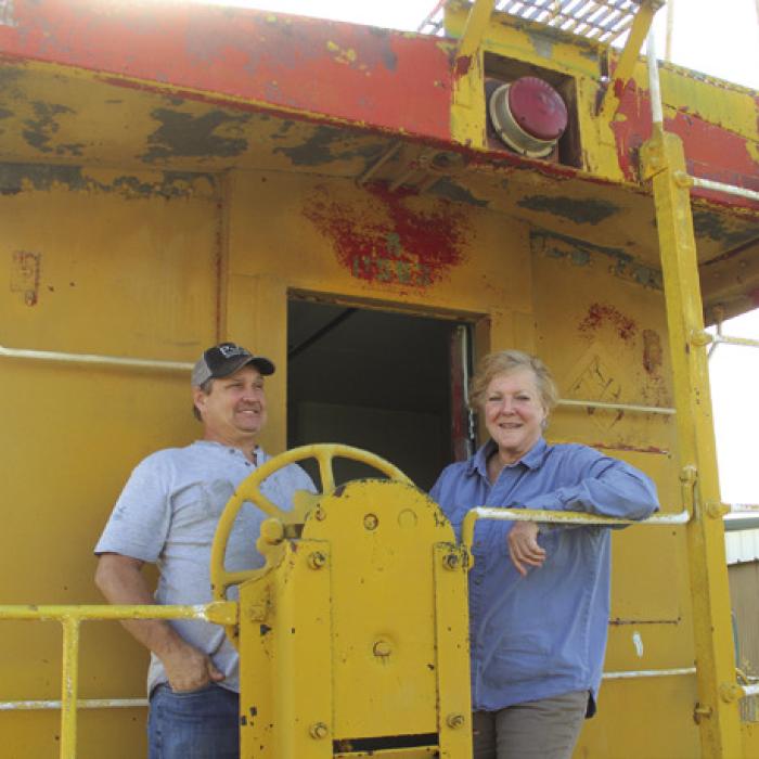 Gary Gillentine, left, and Carlie Brewer, right, stand on the back of the caboose Brewer recently bought to turn into a tiny home. Gillentine is aiding his expertise to the project. Photos by Jeff Wick