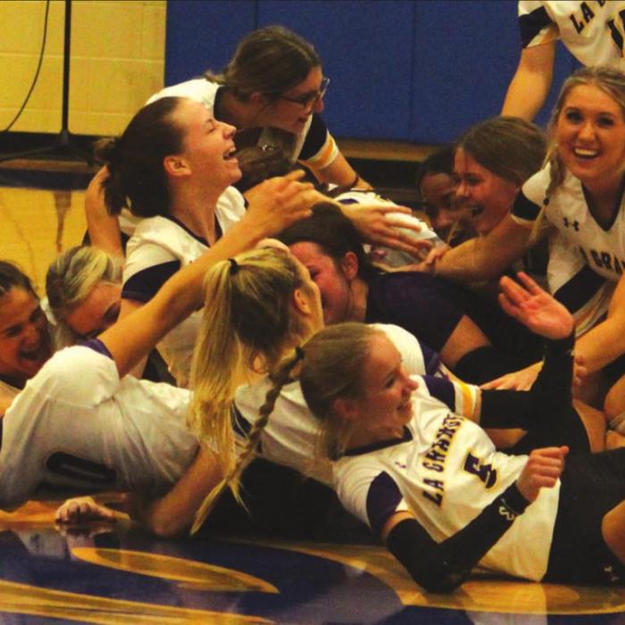 The La Grange girls dog-pile at midcourt in celebration after the Tuesday’s final point. Photo by Jeff Wick