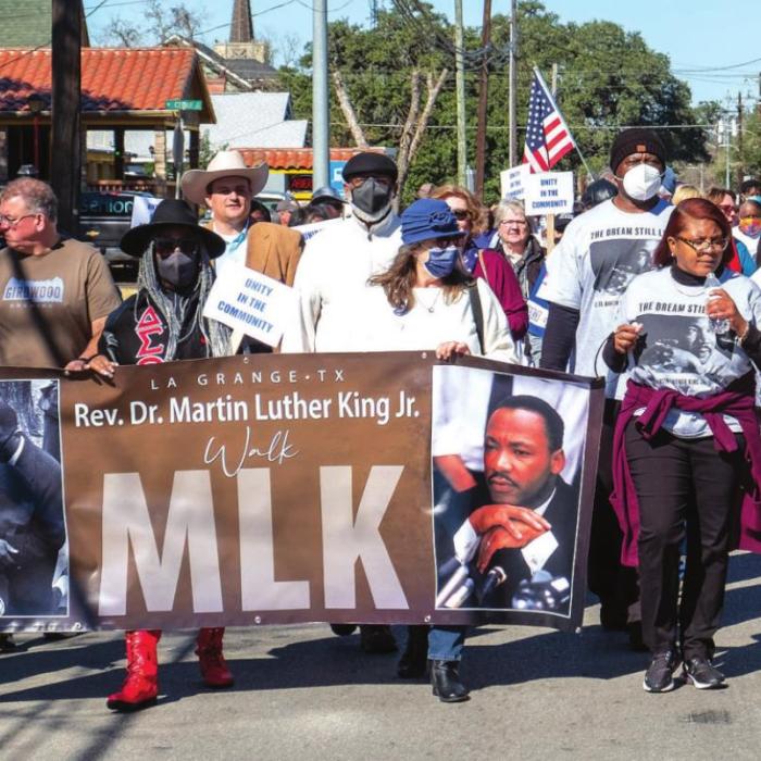 Above, about 100 people participated in the MLK Day Walk as it made its way down Travis St. Below left, Mayor Jan Dockery addresses the audience at the Fayette Public Library Gazebo. Below right, the MLK Day Walk departs from the Courthouse Square on Monday. Photos by Andy Behlen