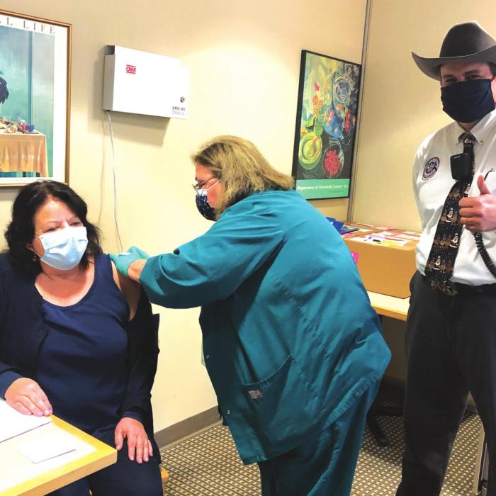 Laurie Quitta, left, Nurse Director of the Medical Surgical Unit of St. Marks Medical Center, gets injected with the COVID vaccine by nurse Dabbie Hinkley, center, as Craig Moreau, Emergency Management Chief, gives a thumbs up.