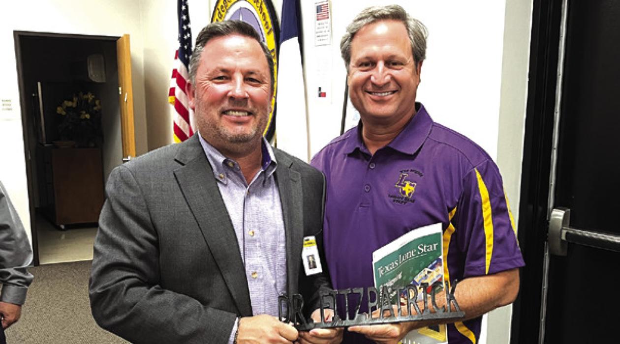 La Grange superintendent Andy McHazlett, left, presents outgoing school board member Dr. Marc Fitzpatrick, right, with his name plate that marked his seat in the board room. Monday was Fitzpatrick’s last meeting. Photo by Jeff Wick