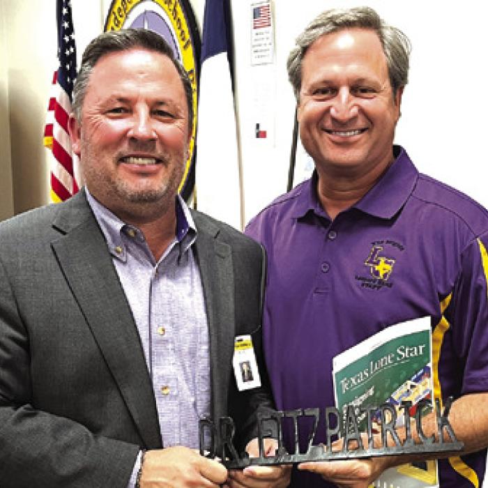 La Grange superintendent Andy McHazlett, left, presents outgoing school board member Dr. Marc Fitzpatrick, right, with his name plate that marked his seat in the board room. Monday was Fitzpatrick’s last meeting. Photo by Jeff Wick