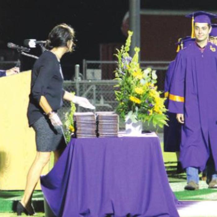 Logan Adamcik, the first alphabetically to officially graduate, walks up to a table where every graduate grabbed their own diploma.