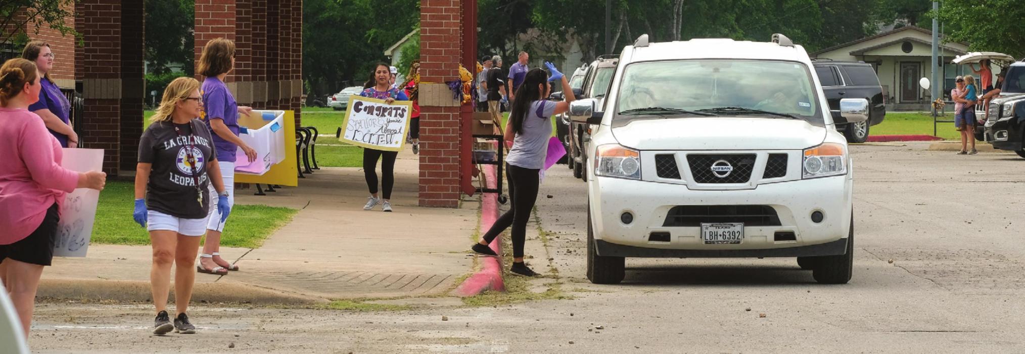 Seniors at La Grange High School picked up their graduation caps and gowns in a drive-through at the school Tuesday, May 5. For most of the students, it was their first visit to campus since spring break, when the school closed for the coronavirus. At the drive-through on Tuesday, teachers and school staff held up motivational signs for the soon-to-be graduates. La Grange ISD has not yet announced plans for a graduation ceremony. Seniors were told to expect a ceremony date in June. Photo by Andy Behlen