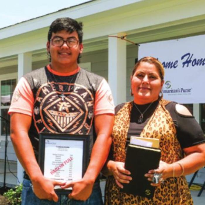 Jose and Francisca Castaneda hold a bible and a bill stamped “paid in full” in front of their new home in Hope Hill. Photo by Andy Behlen