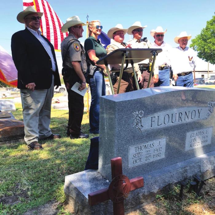 The new memorial cross stands in the foreground in from of T.J. Flournoy’s tombstone as several local dignitaries pose for a photo after Saturday’s ceremony. From left, State Rep. candidate Stan Kitzman, Deputy Michael Krenek, Sgt. Angela Lala, Sgt. Charles Jobb, Deputy Terry Guentert, Fayette County Sheriff &amp; former special Texas Ranger Keith Korenek, and Chief Deputy Randy Noviskie. Photo by Elaine Thomas