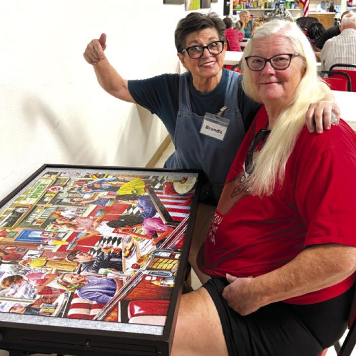 Volunteer Brenda Ray and member Kelly Ortiz show off the puzzle that was completed after many hours of work by many people at Senior Connections.