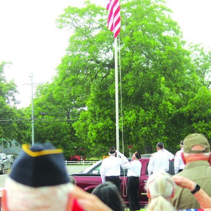 Attendees stand at attention as a new flag is raised during Monday’s ceremony.