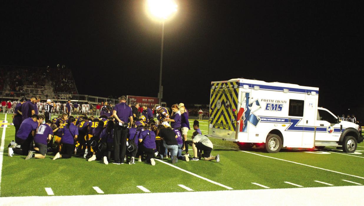The members of the La Grange football team gather to say a prayer prior to the departure of the ambulance carrying Jaren Woods after he broke his leg in Friday’s game.