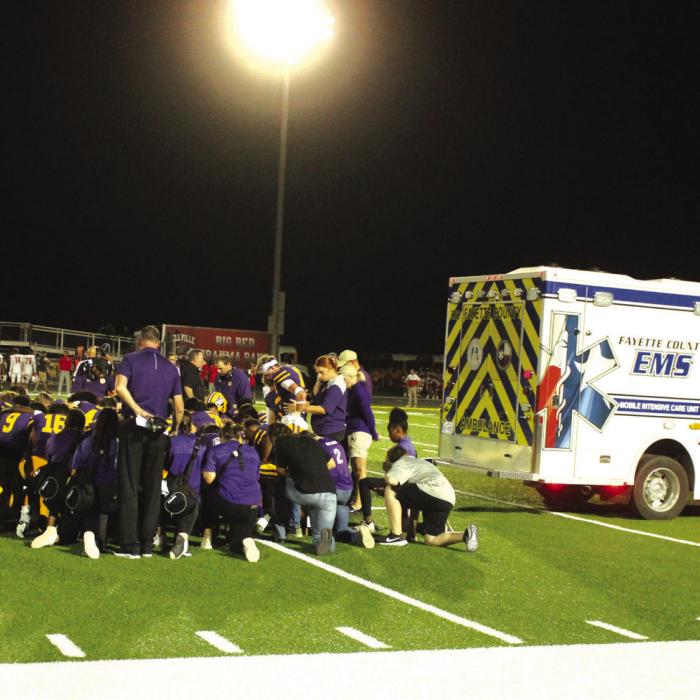 The members of the La Grange football team gather to say a prayer prior to the departure of the ambulance carrying Jaren Woods after he broke his leg in Friday’s game.