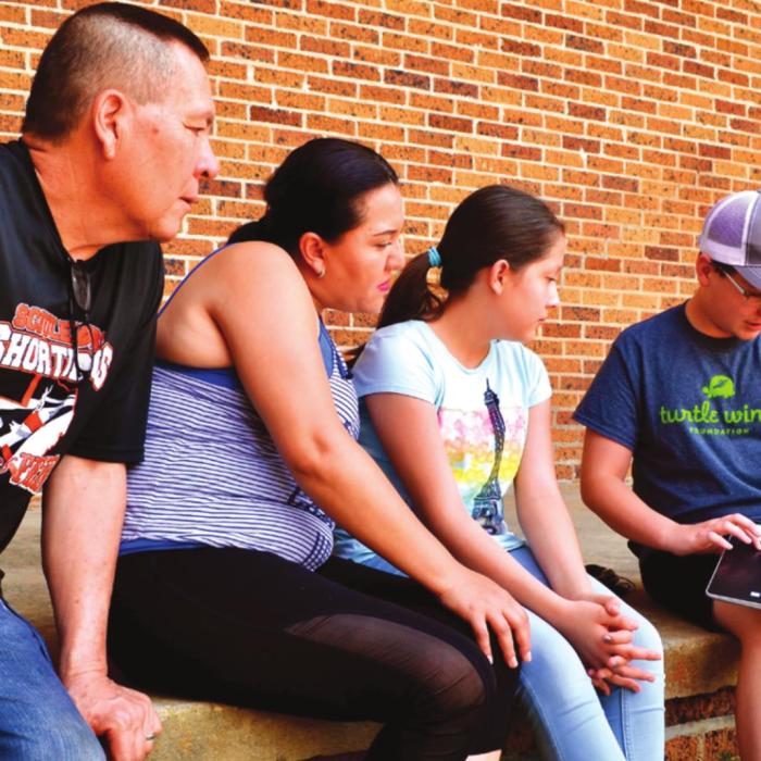 Landon Von Minden (far right) explains to Urbano, Sonia and Emily Gomez how their new computer operates. Sonia will use the machine to work on her GED and Emily will be able to connect with her school on line. Landon is finishing his 8th grade in La Grange.